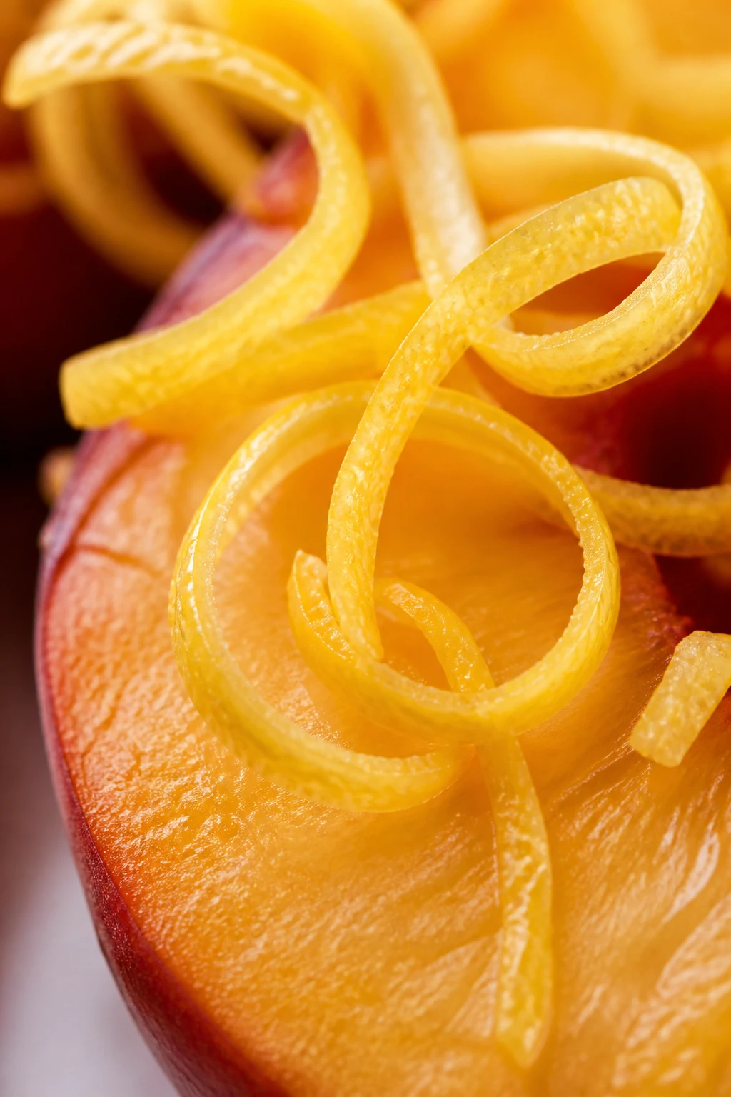 Macro shot of lemon zest spirals over a peach slice