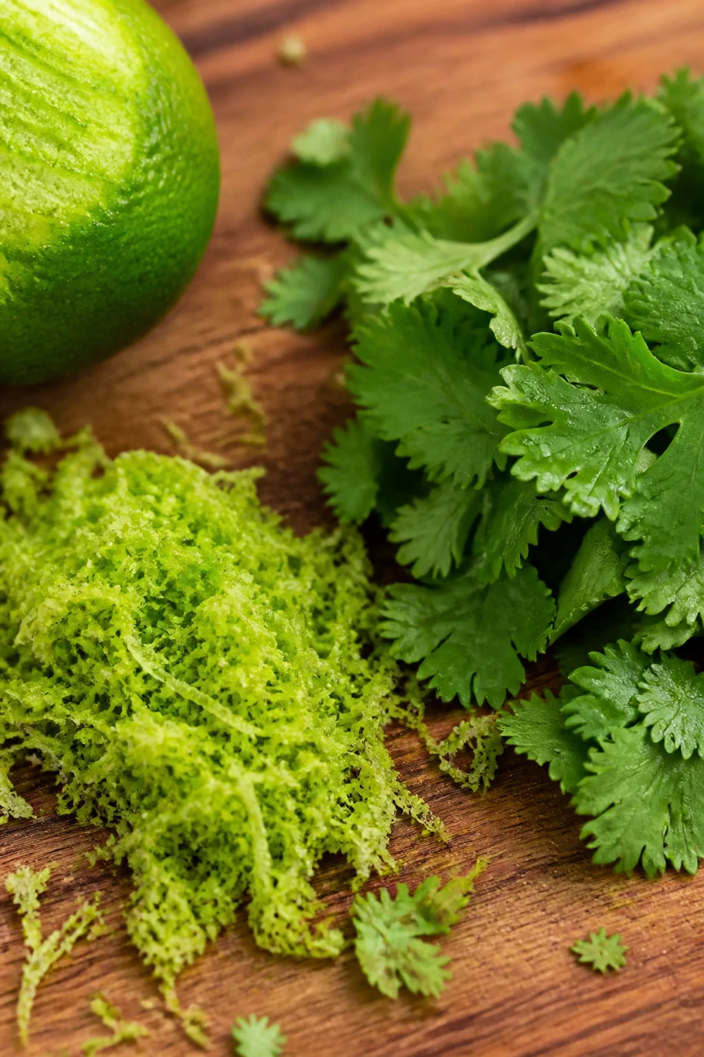 closeup of lime zest and cilantro on wooden cutting board