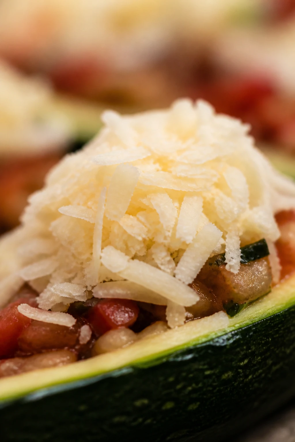 macro shot of a single grated cheese mound on top of a zucchini boat